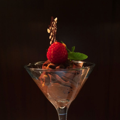 A dessert in a cocktail glass topped with a raspberry.