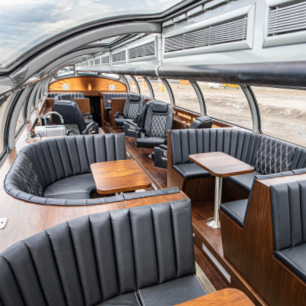 A lounging area surrounded by windows in a train car.