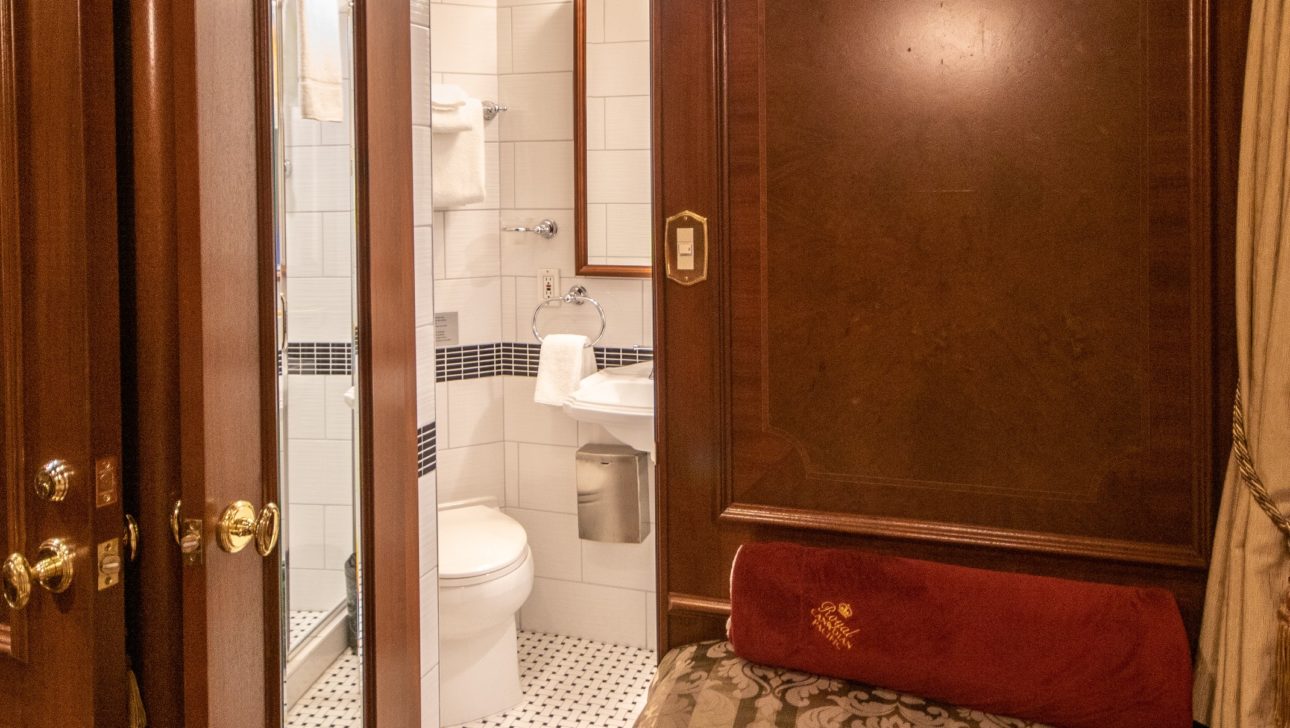 A queen bed in a train car, with accompanying bathroom.