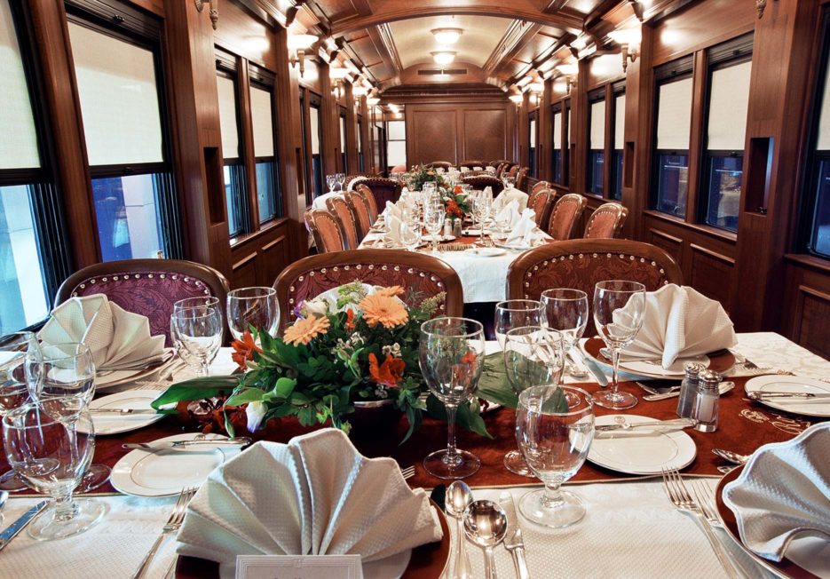 Fully set dining tables inside a railcar.