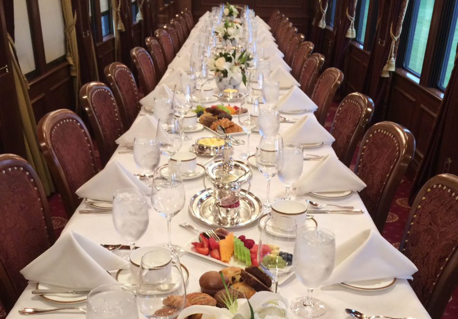 A long, set dining table inside of a railcar.